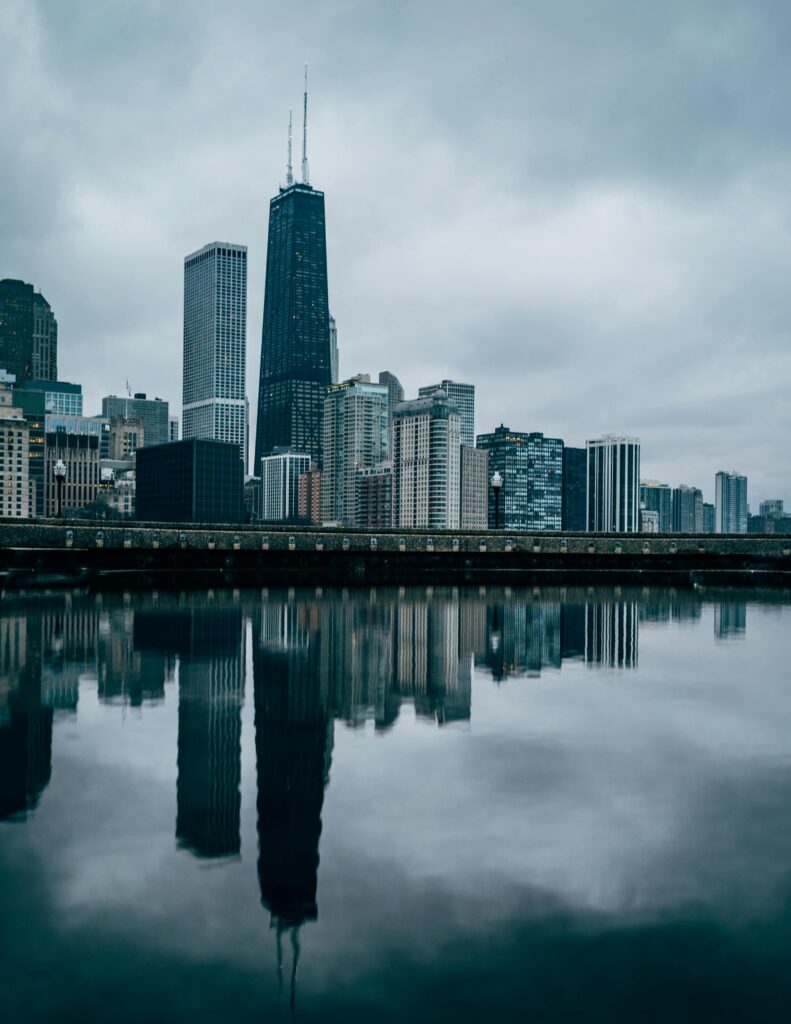 Scenic view of Chicago skyline mirrored in a calm river under overcast skies.